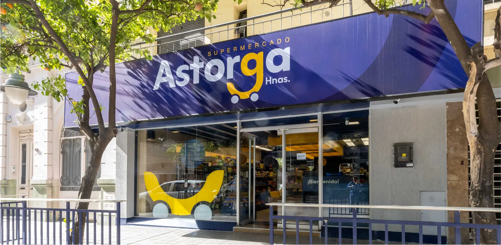Fachada de un supermercado urbano con entrada vidriada y branding destacado Astorga Hnos.