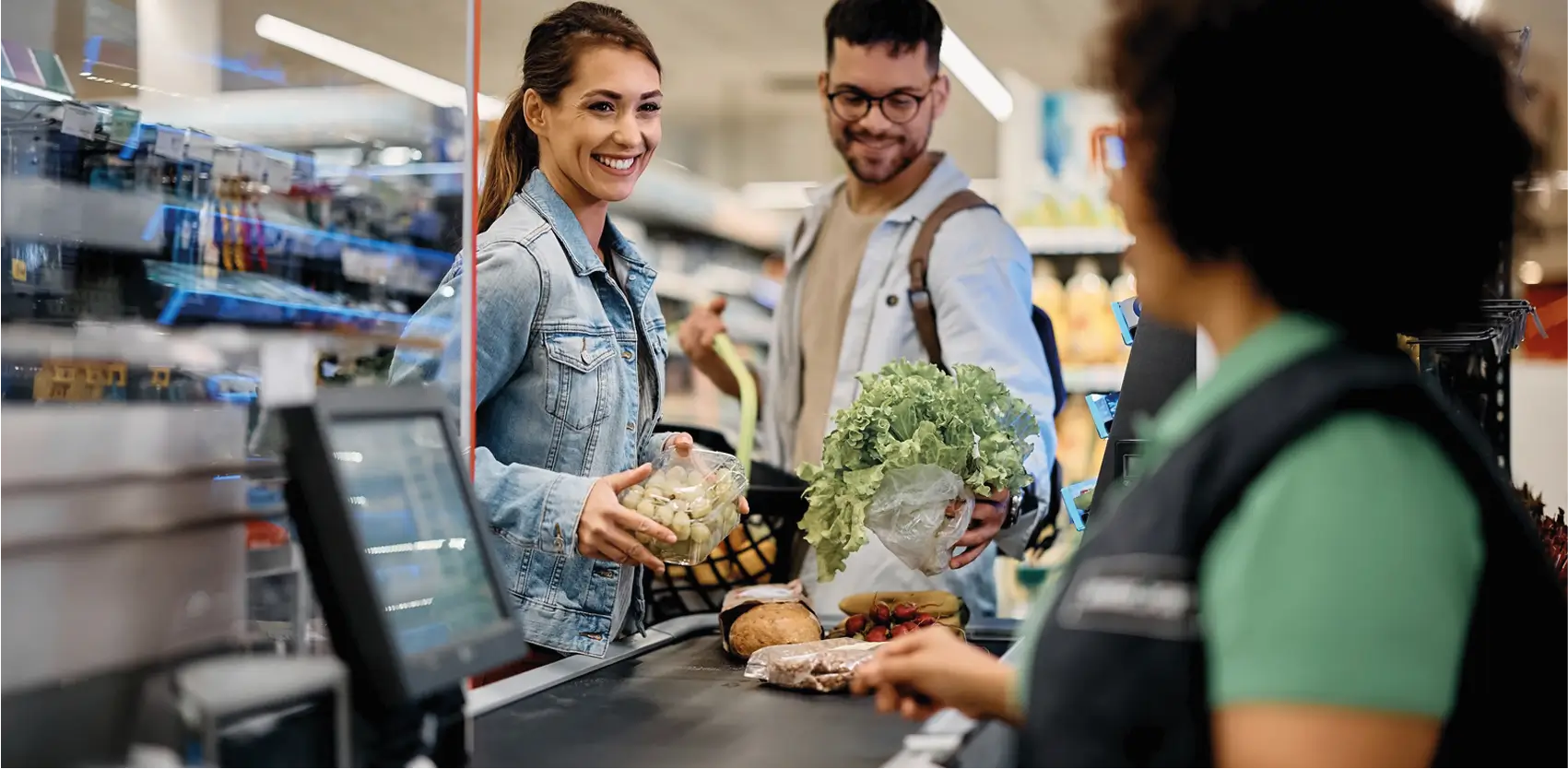 Clientes comprando en supermercado con góndolas comerciales y caja checkout moderna