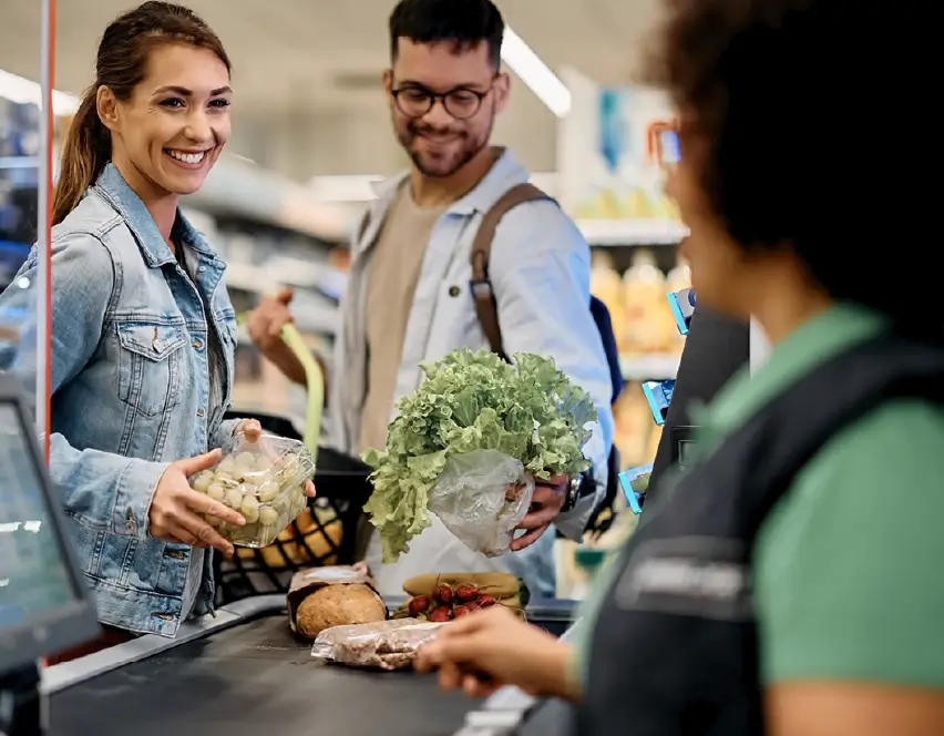 Checkouts modernos y góndolas comerciales para supermercados Pareja realizando compra en supermercado en caja checkout con góndolas comerciales