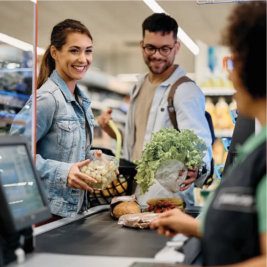 Clientes pagando productos frescos en línea de caja checkout de supermercado