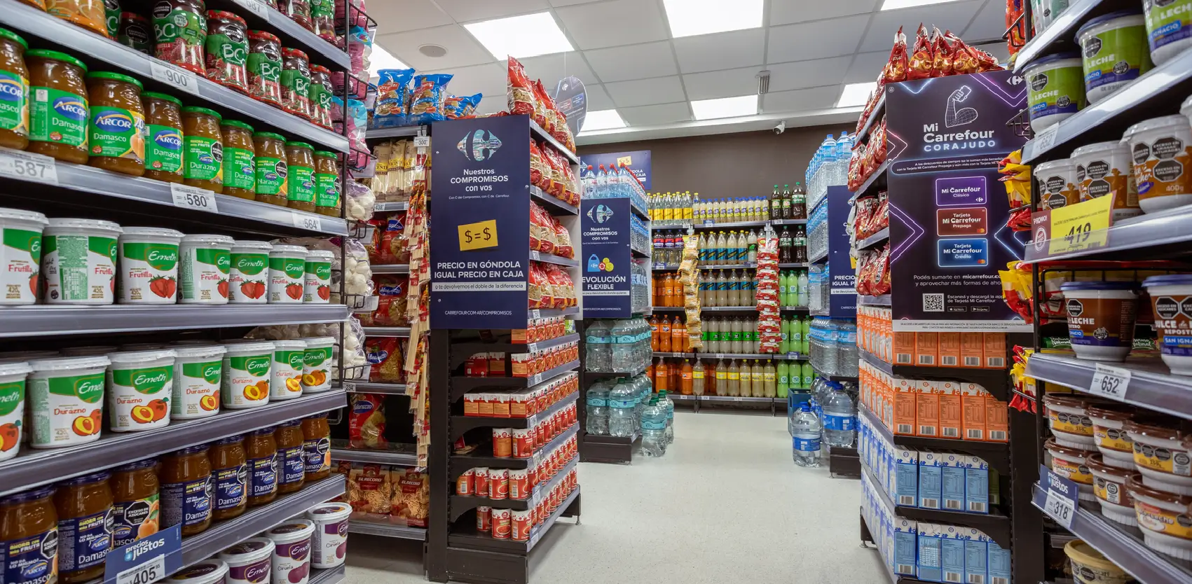 Pasillo de supermercado con góndolas centrales y punteras promocionales organizando productos de consumo masivo